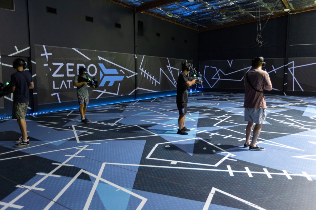 An image of multiple people in a large room that is set up for a virtual reality experience